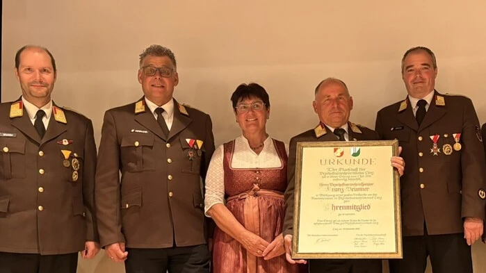 Feuerwehrkameraden stehen mit einer Frau auf einer Bühne