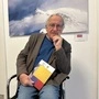 Wilfried Leo Kuß sitzt mit seinem neuen Buch auf einem Stuhl vor einem Gemälde | Wilfried Leo Kuß gründete die Galerie im Drauknie 2012