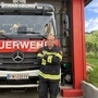 Ein Mann steht mit verschränkten Armen vor einem Feuerwehrauto 