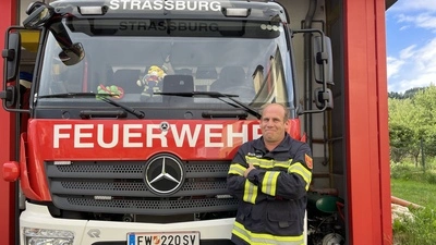 Ein Mann steht mit verschränkten Armen vor einem Feuerwehrauto 