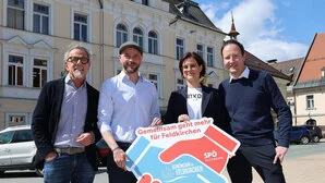 Vier Menschen stehen zusammen und halten ein Transparent in der Hand 
