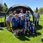 Eine Mannschaft steht jubelnd am Spielfeld und lacht in die Kamera.