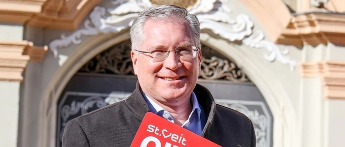 Ein Mann hält eine große rote City Card in den Händen und lächelt in die Kamera.