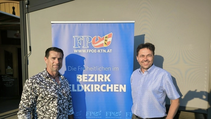 Zwei Herren vor einem FPÖ-Banner. Sie blicken beide in die Kamera.
