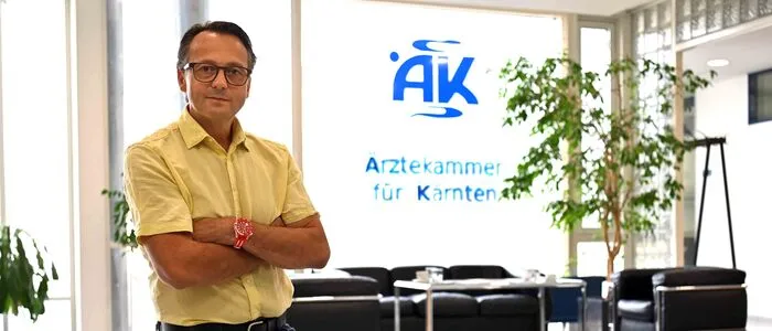 Ein Mann steht vor einem Fenster mit der Aufschrift „Ärztekammer für Kärnten“