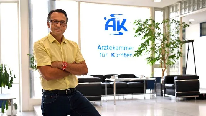 Ein Mann steht vor einem Fenster mit der Aufschrift „Ärztekammer für Kärnten“
