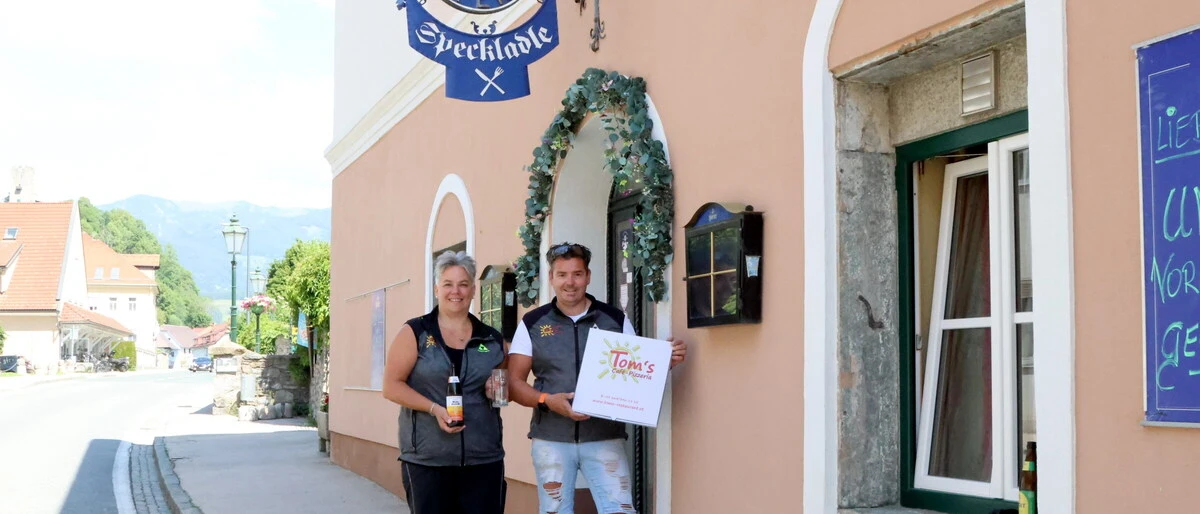 Ein Mann und eine Frau stehen vor einem Gasthaus und posieren für ein Foto.
