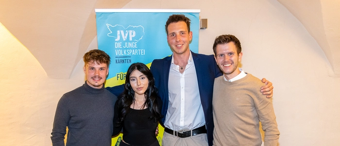 Drei junge Männer und eine junge Frau posieren für ein Foto und lächeln in die Kamera.