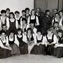 Ein schwarzweiß Foto. Menschen in Tracht stehen als Gruppe zusammen 