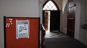 Der Eingangsbereich einer Kirche mit einem Hinweisschild, dass dieser Bereich videoüberwacht wird | Ein Schild weist auf die Videoüberwachung hin 