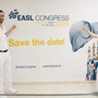 Eine Ärztin und ein Arzt stehen vor einer Wand, die auf den größten Leberkongress in Europa hinweist.