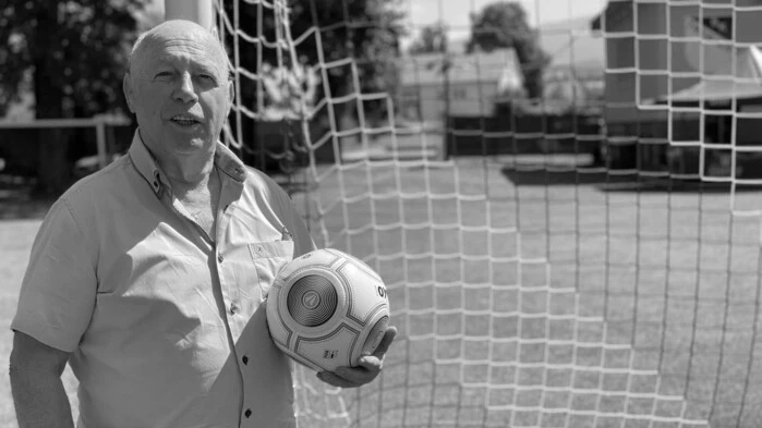 Ein Mann steht vor einem Tor mit einem Fußball in der Hand 