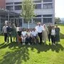 Eine Gruppe von Menschen posiert bei Sonnenschein für ein Foto.