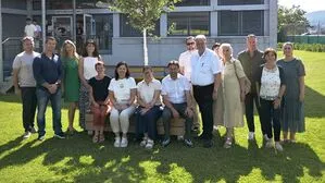 Eine Gruppe von Menschen posiert bei Sonnenschein für ein Foto.