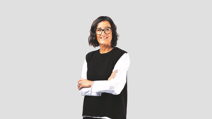 Eine Frau steht vor einer Wand und lacht in die Kamera