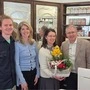 Vier Menschen in einer Apotheke. Ein Blumenstrauß wurde überreicht. 