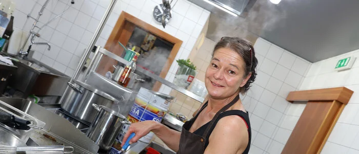 Eine Frau steht in der Küchte hinter einem Grill