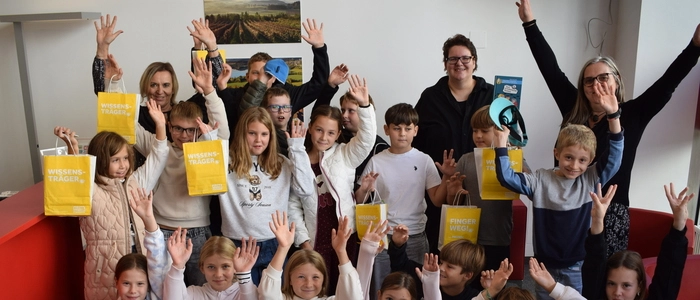 Eine Schulklasse mit bunten Papiertüten in der Hand, sie grinsen in die Kamera.