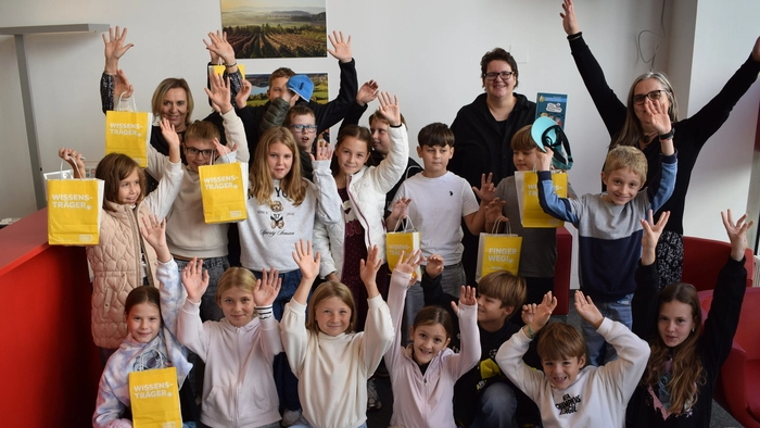 Eine Schulklasse mit bunten Papiertüten in der Hand, sie grinsen in die Kamera.