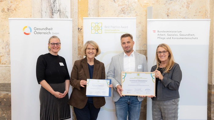 Vier Menschen halten ein Plakat in der Hand und lachen in die Kamera