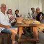 Eine Runde von Menschen sitzt an einem Tisch, alle genießen ein Glas Wein.