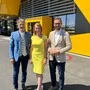 Zwei Männer und eine Frau lächeln bei Sonnenschein in die Kamera.