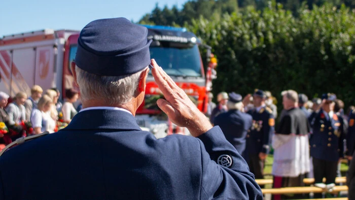 Ein Feuerwehrmann salutiert vor einem neuen Feuerwehr-Fahrzeug.