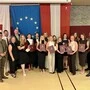 Viele Schülerinnen und Schüler halten ihre Maturazeugnisse in den Händen und lächeln in die Kamera.