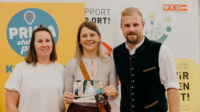 Zwei Frauen und ein Mann lächeln in die Kamera.