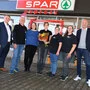 Sieben Personen posieren vor dem neuen Spar-Express in Feldkirchen. | Die Socar-Tankstelle hat mit einem Spar-Express-Shop neueröffnet