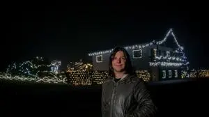 Ein Mann steht vor einem Haus. Im Hintergrund sind Lichterketten angebracht  | Christopher Kampl hat 300.000 Lichter auf seinem Grundstück angebracht 