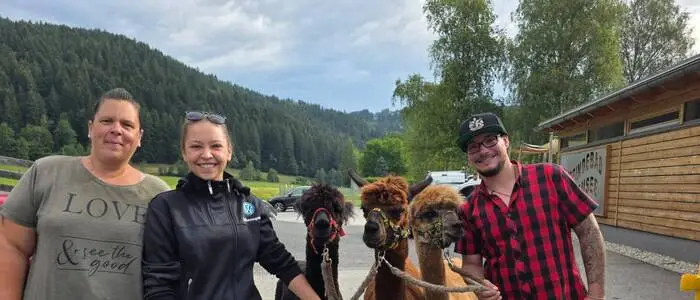 Drei Menschen und zwei Alpakas schauen in die Kamera