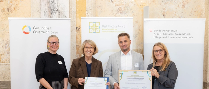 Vier Menschen halten ein Plakat in der Hand und lachen in die Kamera
