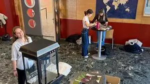 Menschen stehen in einem Saal und basteln.