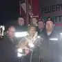 Ein paar Feuerwehrmänner stehen beisammen. Einer trägt eine Katze auf dem Arm.