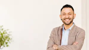 Ein Mann mit verschränkten Armen lächelt in die Kamera 