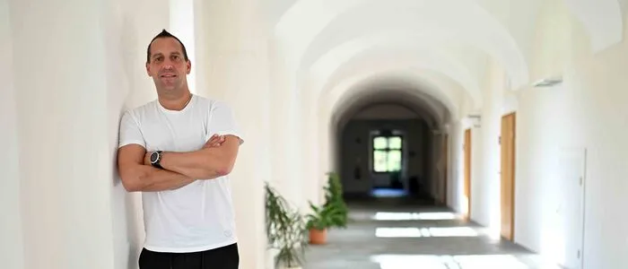 Ein Mann steht in einem Gang angelehnt an einer Mauer. Im Hintergrund ein schwarzes Loch