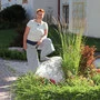 Eine Frau in der Natur. Sie stützt ihren Fuß an einem großen Stein ab. 