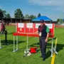 Ein Mann steht bei sonnigem Wetter auf einem Sportplatz und lächelt in die Kamera.