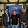 Drei Männer posieren vor einem FPÖ-Plakat für ein Foto.