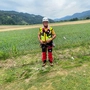 Ein Mann steht mit einer Bergrettungsausrüstung vor einem Maisfeld.