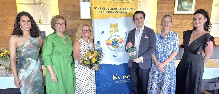 Fünf Frauen und ein Mann posieren für ein Foto und lächeln in die Kamera.