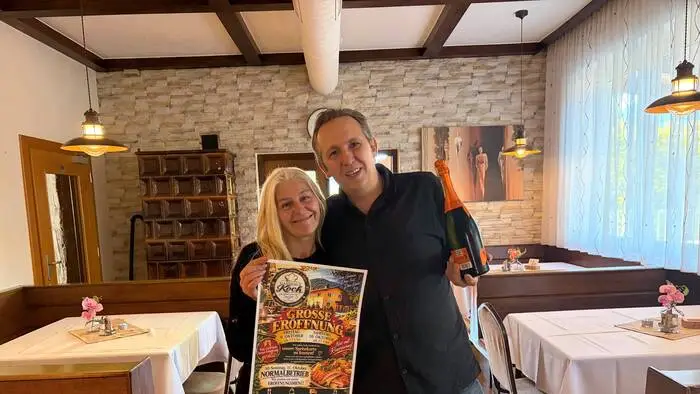 Eine Frau und ein Mann lächeln in die Kamera. Die Frau hält ein Plakat in der Hand.