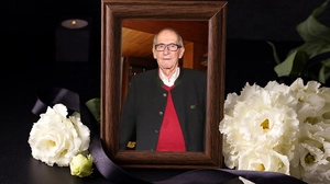 Ein Foto in einem schwarzen Rahmen, daneben ein Trauerbouquet.