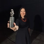 Eine Frau hält eine kleine Trophäe in die Kamera 