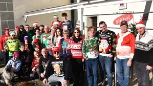 Männer und Frauen in bunten Weihnachtspullovern gekleidet stehen vor dem Lokal „Stifterl“ in Eberndorf | Die Teilnehmer der „Wer trägt den schiachsten Weihnachtspullover“-Challenge aus dem Vorjahr