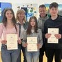 Drei Schüler stehen mit Urkunden in der Hand vor zwei Lehrern