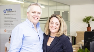 Das Geschäftsführungsduo Walter Huber und Katrin Galambos-Huber steht nebeneinander im Büro und lächelt in die Kamera
