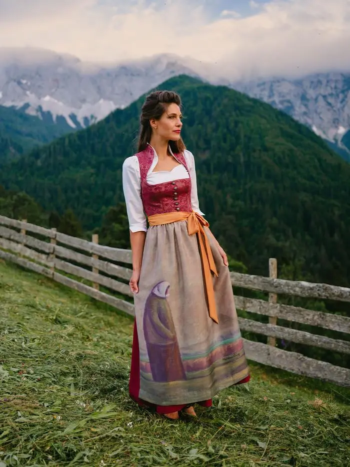 Dirndlschürze „Die Schreitende“ mit dem weinroten Basisdirndl