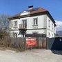 Auf dem Bild sieht man ein graues Haus mit Zaun runderherum. Auf dem Zaun hängt das Banner der Baufirma Rus